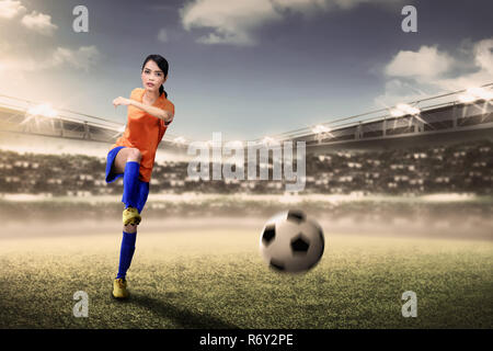 Footballeur asiatique attrayant kicking ball au cours de match femme Banque D'Images