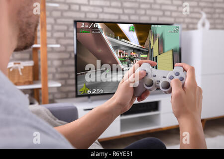 Portrait d'un homme avec la manette de jeu Jouer à la télévision Banque D'Images