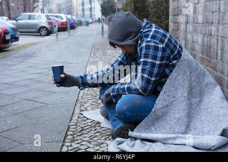 Mendiant Holding Disposable Cup Banque D'Images