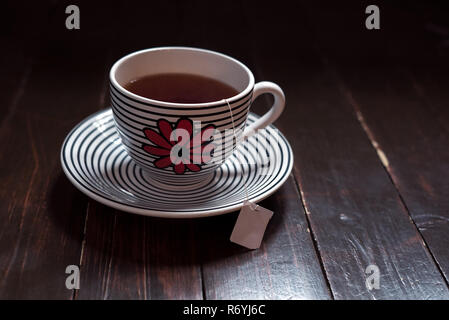 Sachet de thé vert et l'intérieur d'une grande tasse avec soucoupe sur bois vintage Banque D'Images