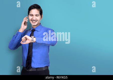 Smiling asian businessman vérifier la montre tout en parlant au téléphone Banque D'Images