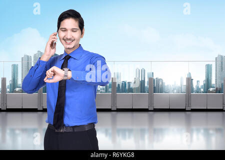 Happy asian businessman with phone contrôle de la montre Banque D'Images