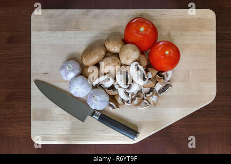 Gousses d'Ail Tomates champignons couteau de cuisine sur une planche à découper Banque D'Images