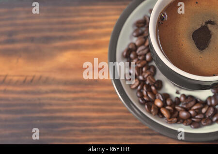 Un bol vert avec du café sur une soucoupe avec café en grains Banque D'Images