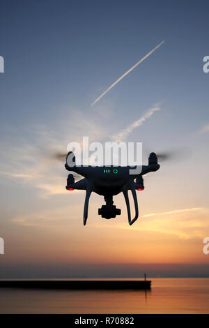 Drone télécommandé équipé de photo aérienne et vidéo planant dans l'air et le coucher du soleil Banque D'Images