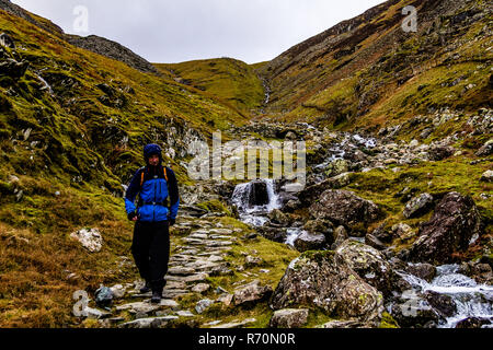 Un froid humide braves Walker de la Petite Venise, le Lake District, UK. La position de tête à Rosthwaite Dale. En décembre 2018. Banque D'Images