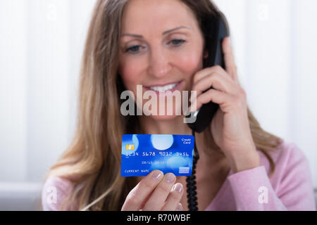 Woman Holding Credit Card While Talking On Telephone Banque D'Images