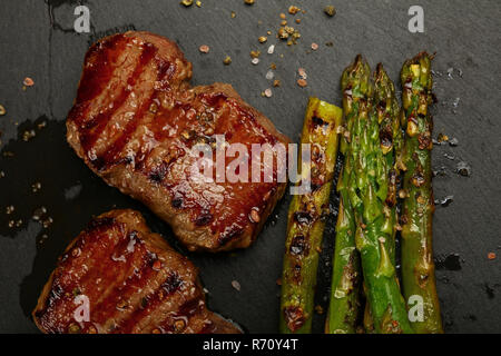 Close up boeuf grillé steaks sur plaque en ardoise noire Banque D'Images