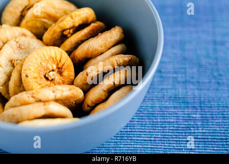 Vue de dessus du bol bleu rempli de tas de figues séchées sucré et composé de tissu bleu Banque D'Images