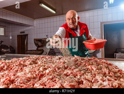 Ligne de production de saucisses. Butcher piquant la chair de saucisses Banque D'Images