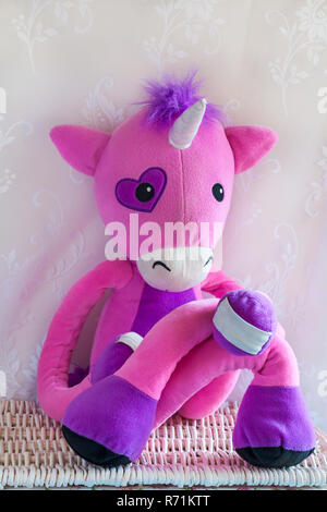 Stretchkins peluche Licorne sitting cross legged sur panier en osier Banque D'Images