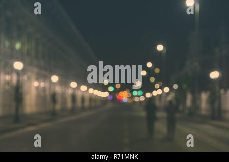 Image floue de personnes marchant dans une rue de la ville avec voiture vide dans la nuit Banque D'Images