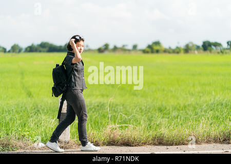 Femme avec sac à dos randonnée le long d'une route Banque D'Images