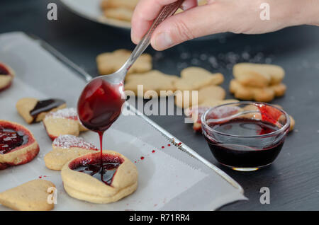 Les cookies en forme de cœur sur un fond de bois. Femme se déverse sur le bourrage des cookies. Banque D'Images