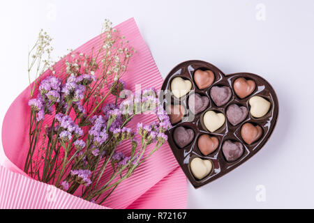 De belles fleurs avec boîte de chocolats en forme de coeur sur fond blanc Banque D'Images