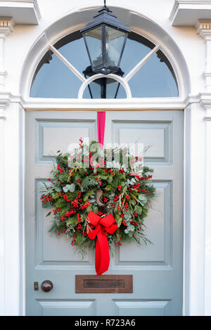 Couronne de Noël avec ruban rouge sur une porte de maison à Broadway. Cotswolds, Worcestershire, Angleterre Banque D'Images