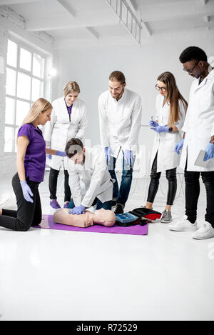 Groupe de jeunes médecins pratiquant à faire la respiration artificielle avec des nuls au cours de la formation aux premiers secours dans la chambre blanche Banque D'Images