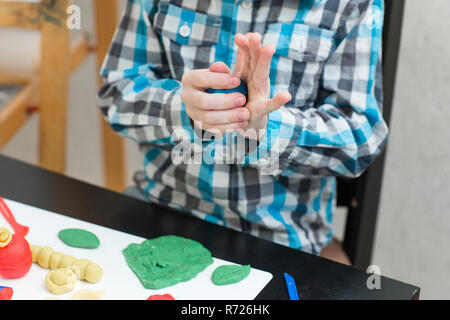 Garçon Blond sculpte à partir de pâte à modeler à la maison à la table. L'idée et concept de l'école, l'école, la maison de l'éducation et activités de développement. Banque D'Images