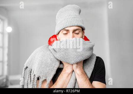 Portrait d'un homme enveloppé dans un cadre chaleureux et foulards hat se sentir mal d'avoir une maladie d'hiver à l'intérieur Banque D'Images