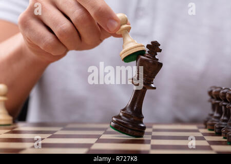 Close-up de la main d'un homme vaincu King Chess Piece avec pion Banque D'Images