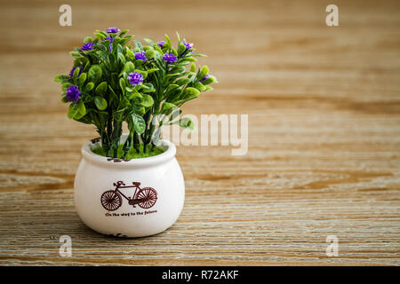 Coloré de fleurs artificielles en pot blanc sur fond de bois Banque D'Images