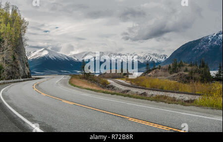 Une route de l'Alaska : La Seward Highway sous courbes nuageux alors qu'il passe par les montagnes couvertes de neige au bord de l'océan au sud de l'entrée d'Anchorage. Banque D'Images