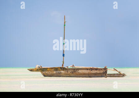 Bateau en bois en Dhow couché au sec à marée basse sur une plage tropicale à l'Océan Indien près de Zanzibar, Tanzanie Banque D'Images