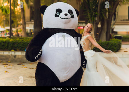 Un homme dans un costume de panda un confort femme blessée Banque D'Images