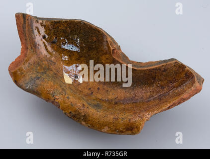 Fragment de poterie, misbaksel casserole casserole casserole, porte-ustensiles de cuisine Faïence Céramique faïence glaze glaçure de plomb à la main, cuit glacé tourné à fond de jante télévision fragment. Large Bord supérieur avec bec verseur. L'écharde rouge glacé à l'interne. Misbaksel : pan est déformé la partie inférieure affiche le bombement des restes de frittés glaçure cuite curieusement archéologie poterie fosse souterraine le centre-ville de Rotterdam Stadsdriehoek indigènes de Groenendaal la préparation des aliments la poterie artisanale poterie cuisine découverte du sol : fosse souterraine 1975-10-05 de Groenendaal. Banque D'Images