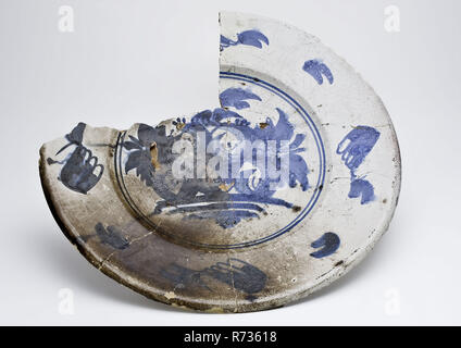 Plat à décor majolique en bleu sur fond blanc avec des fruits que performance, lave vaisselle Faïence Céramique trouver sol support étain glaze glaçure plombifère de glacis à la main, cuits sous tension 2x plat de majolique majolique décoré en bleu sur fond blanc. Pour montrer cinq fruits pommes ou poires à l'arrière-plan une laisse deux cercles bleus de l'épaule. Sur le large bord blanc une feuille séparée possible sur l'extérieur de motifs émaillés fine avec du plomb à l'intérieur, le glacis couche de glacis est partiellement parsemée et repéré l'archéologie de terrain de l'héliport de Rotterdam poterie autochtone prix alimentaire table de service desservant la discothèque Banque D'Images