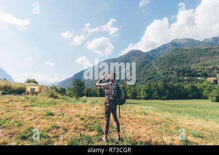 Young male hiker binoculars vers les montagnes, Primaluna, Trentino-Alto Adige, Italie Banque D'Images