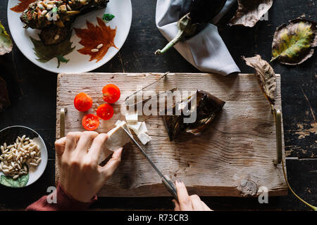 Woman slicing rustique fromage sur planche, vue de dessus de mains Banque D'Images