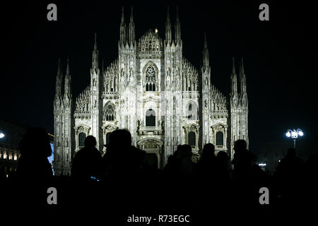 Noël à Milan, Italie. Silhouette de personnes en face de la cathédrale du Duomo façade illuminée la nuit. Banque D'Images