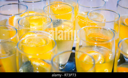 Verres de champagne sur un plateau avec du prosecco et des tranches d'orange dans la lumière du soleil Banque D'Images