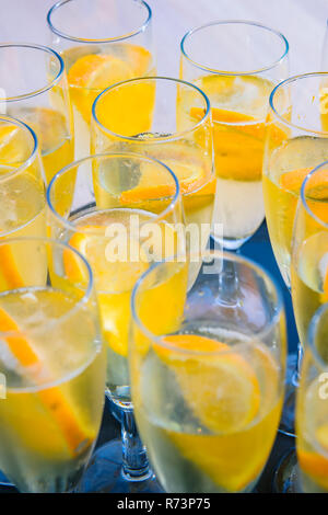 Verres de champagne sur un plateau avec du prosecco et des tranches d'orange dans la lumière du soleil Banque D'Images