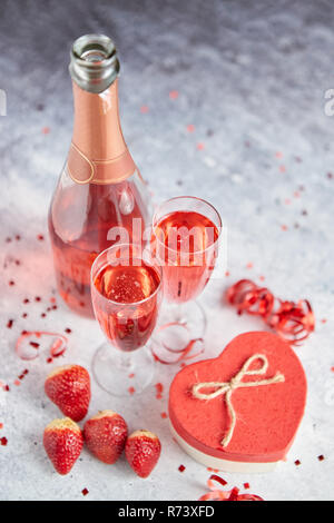 Bouteille de champagne rose, les verres avec des fraises fraîches et des cadeaux en forme de coeur Banque D'Images