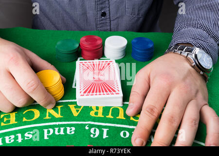 Jetons de Casino et pile de cartes sur table verte. L'homme d'affaires élégant mains. Les problèmes de jeu concept abstrait. Banque D'Images