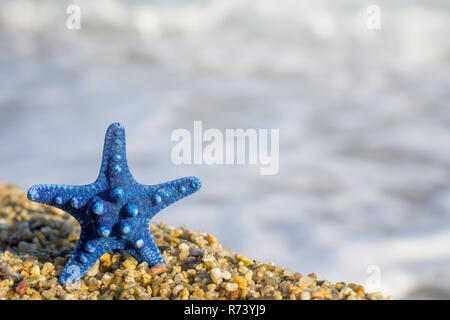 L'étoile bleue épinglée sur le sable à la plage. Bleu de la mer sur l'arrière-plan. Banque D'Images
