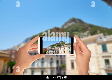 Un touriste prend une photo de la ville de Amalfi de l'escalier de la Duomo local dans un clair d'été journée ensoleillée sur un téléphone mobile Banque D'Images