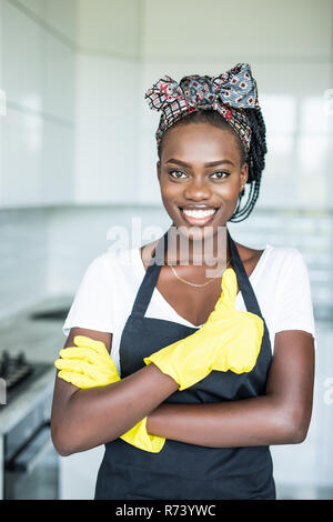 Jeune femme africaine en gants jaunes qui showing thumb up dans la chambre Banque D'Images