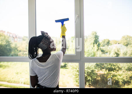 Femme africaine avec verre nettoyage Nettoyant vitre en caoutchouc Banque D'Images