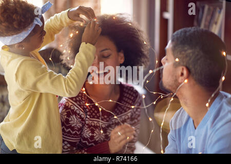 Beau jeune famille jouissant de sa maison de temps ensemble, décorant les lumières de Noël et s'amuser Banque D'Images