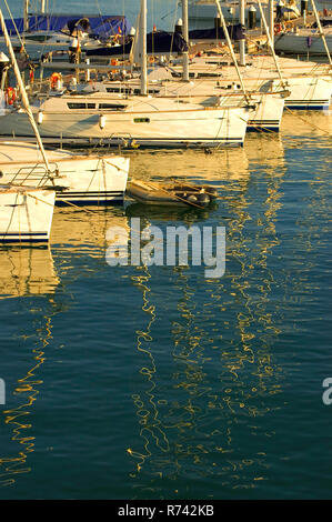 Plusieurs yachts amarrés à la marina et réflexions dans le eau au coucher du soleil Banque D'Images