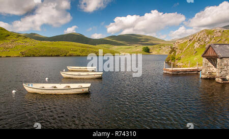 Trois barques traditionnelles sont amarrés dans Llyn y Dywarchen, un petit réservoir et lac de pêche près de Rhy-Ddu dans le parc national de Snowdonia, le Nord du Pays de Galles Banque D'Images