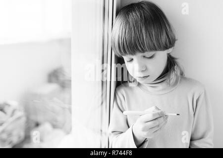 Garçon enfant thermomètre mesure la température. Température élevée sur le thermomètre. Banque D'Images