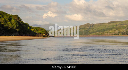 Moutons paissent sur les rives de l'Afon Dwyryd estuaire, avec les montagnes de Snowdonia et un train sur le pont pont de chemin de fer Briwet au loin. Banque D'Images