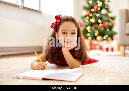 Petite fille écrit la liste de souhaits de Noël à la maison Banque D'Images