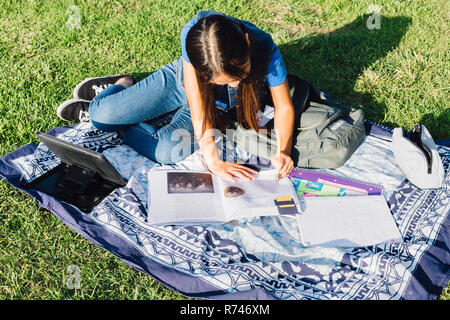 Girl doing homework on grass Banque D'Images