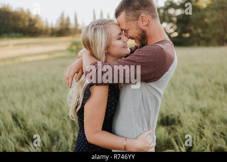 Homme romantique et petite amie hugging dans domaine de l'herbe longue Banque D'Images