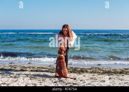 Woman élégantes sur la plage de flatter son chien, Odessa, Odeska oblast, Ukraine Banque D'Images